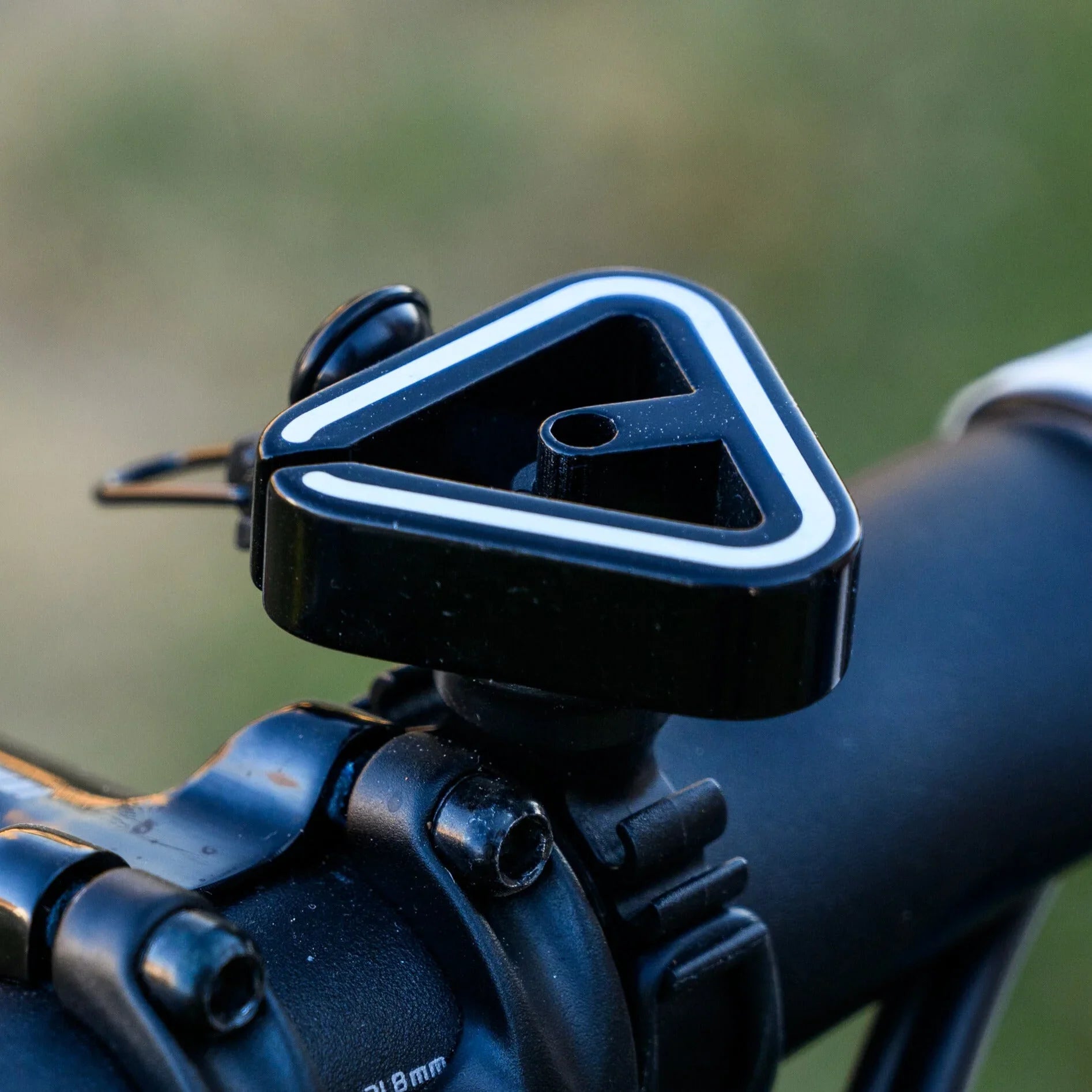Close-up of a black triangular bike handlebar mount with a white outline