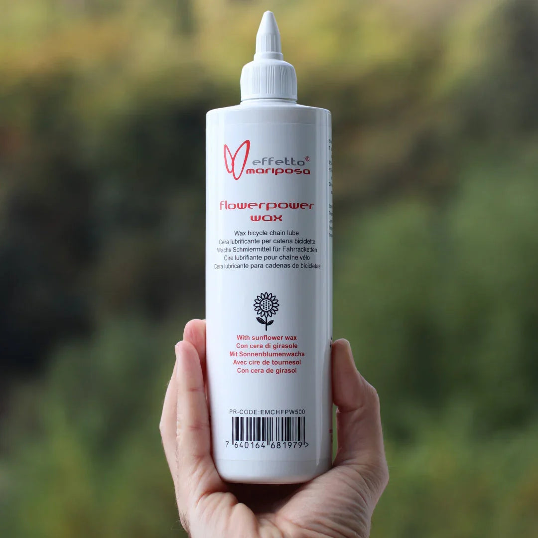 Hand holding Effetto Mariposa Flowerpower Wax bicycle chain lube bottle outdoors