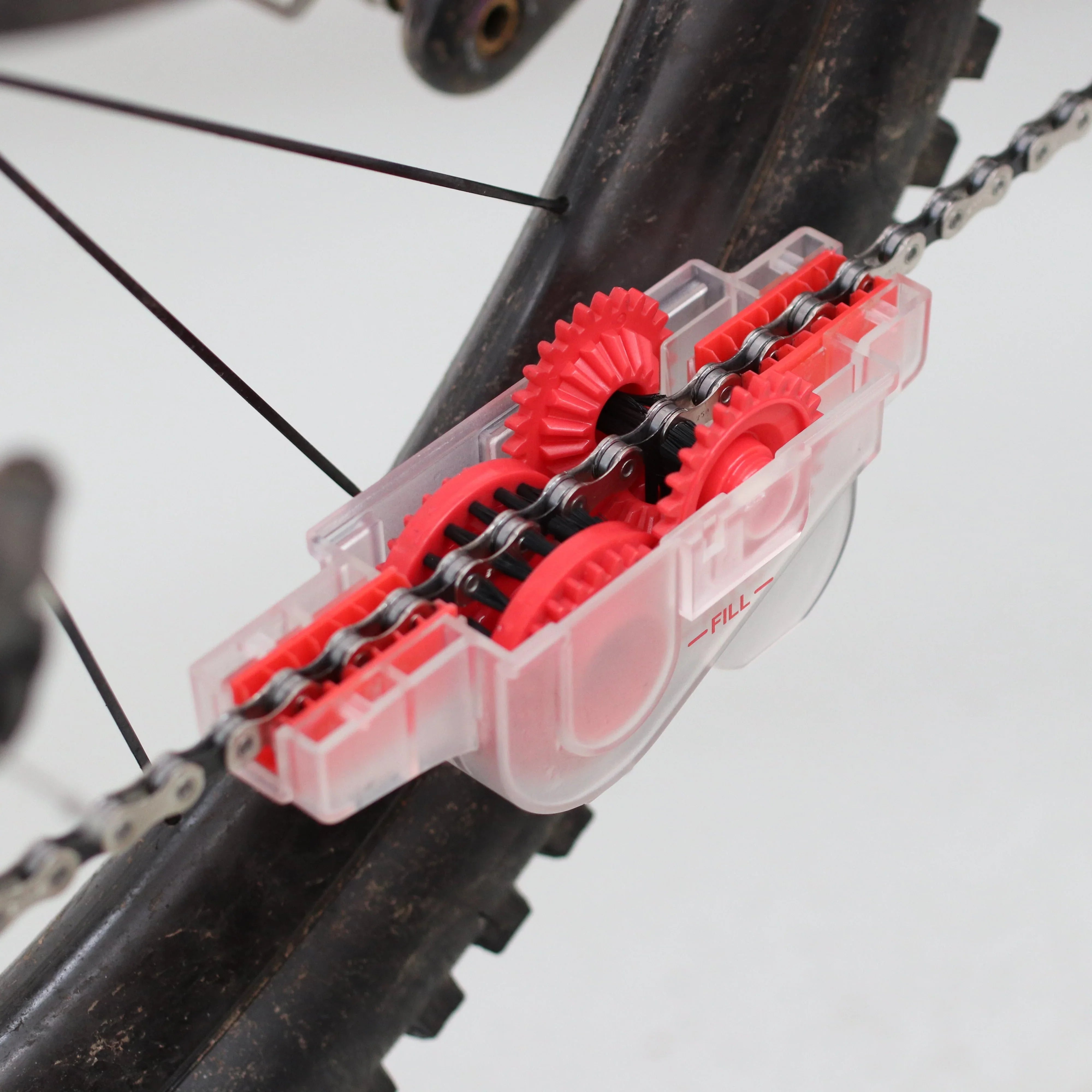 Bicycle chain cleaner tool with red gears attached to bike chain for maintenance