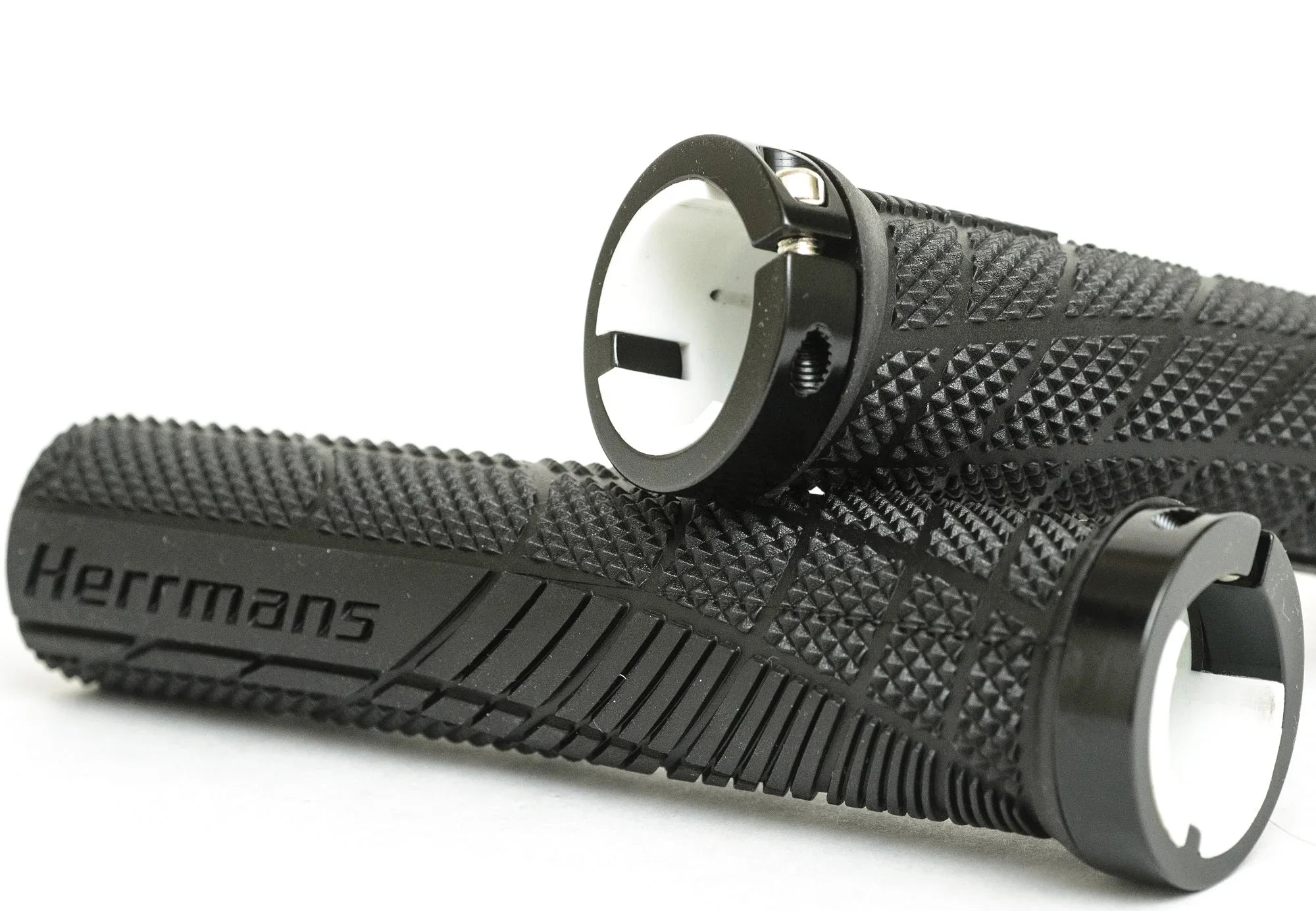 Close-up of black textured bicycle handlebar grips with locking rings and Herrmans logo