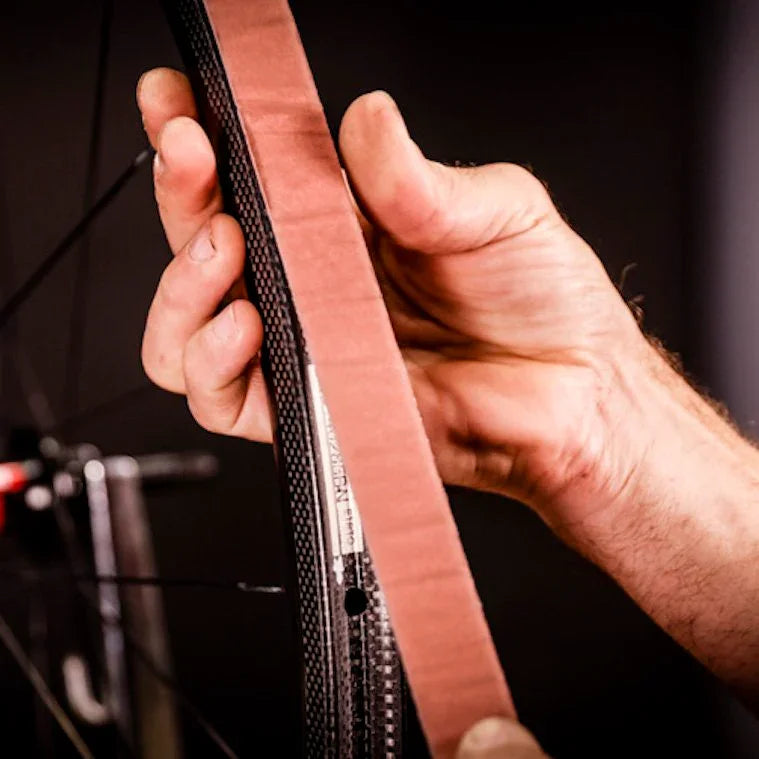 Hand applying tubular rim tape to a carbon bicycle wheel for tire installation