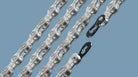 Close-up of silver bicycle chains with quick links on a blue background