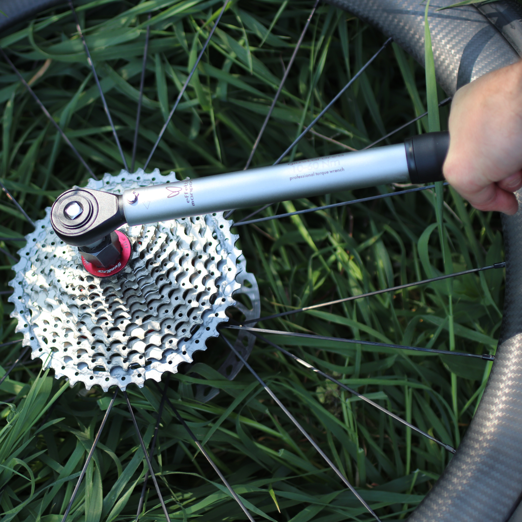 Person using a Giustaforza 1-60 Pro torque wrench on a bicycle wheel with a cassette on grass